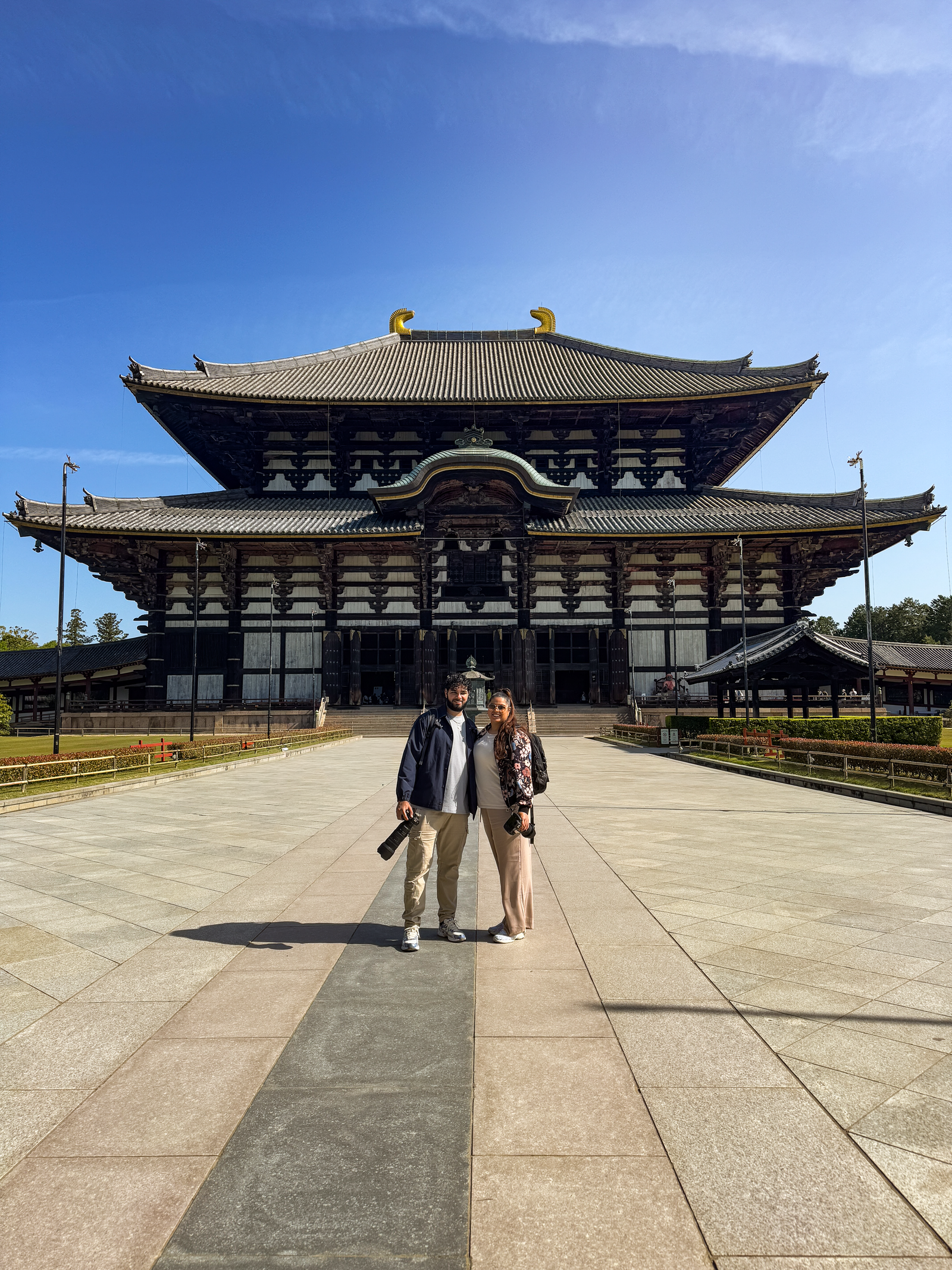 Reiskoppel Arif en Odessa staan voor een grote tempel in Nara met beide een camera in hun hand